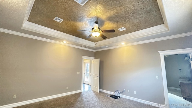 carpeted spare room featuring a tray ceiling, visible vents, and baseboards