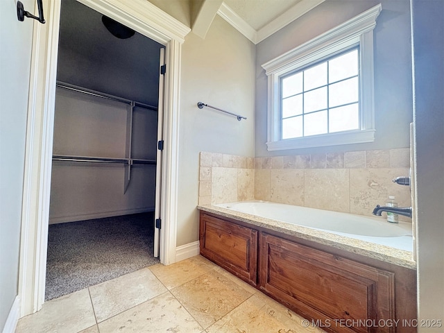 bathroom with a walk in closet, tile patterned floors, crown molding, and a bath