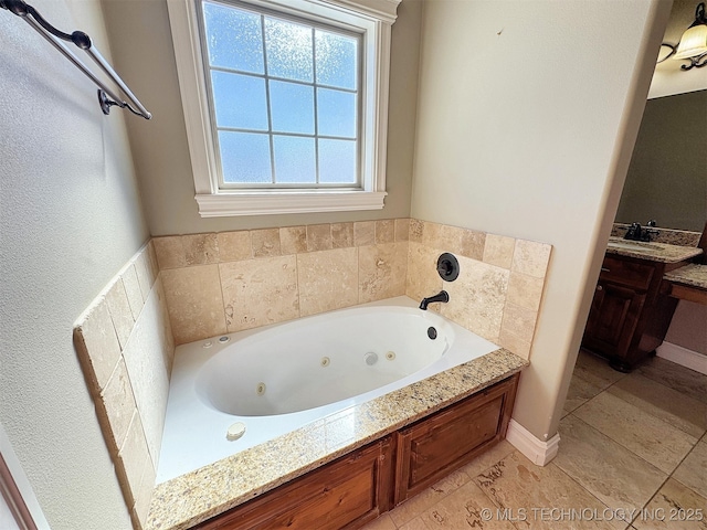 bathroom featuring baseboards, a jetted tub, and vanity