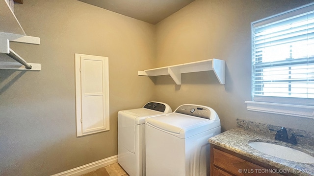 laundry area featuring laundry area, baseboards, washer and dryer, and a sink