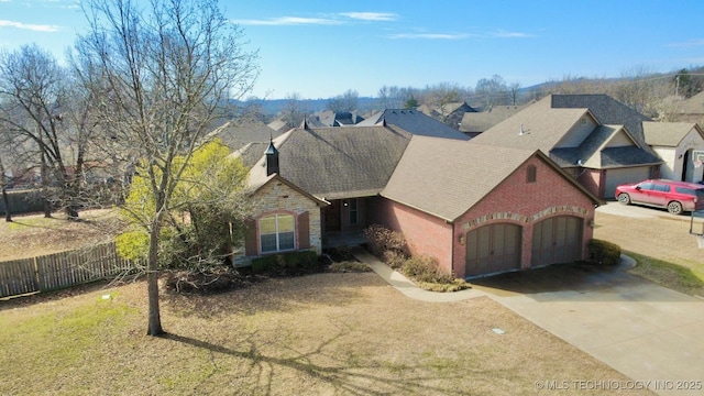 view of front facade with brick siding, concrete driveway, an attached garage, fence, and stone siding