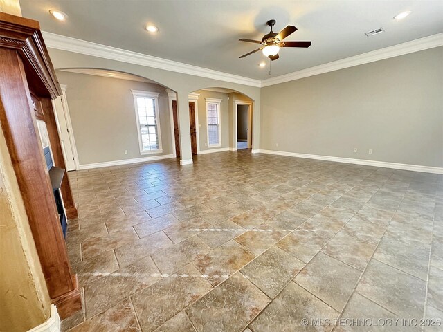 empty room with ornamental molding, arched walkways, visible vents, and baseboards