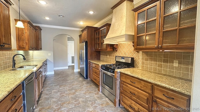 kitchen with visible vents, arched walkways, stainless steel appliances, premium range hood, and a sink