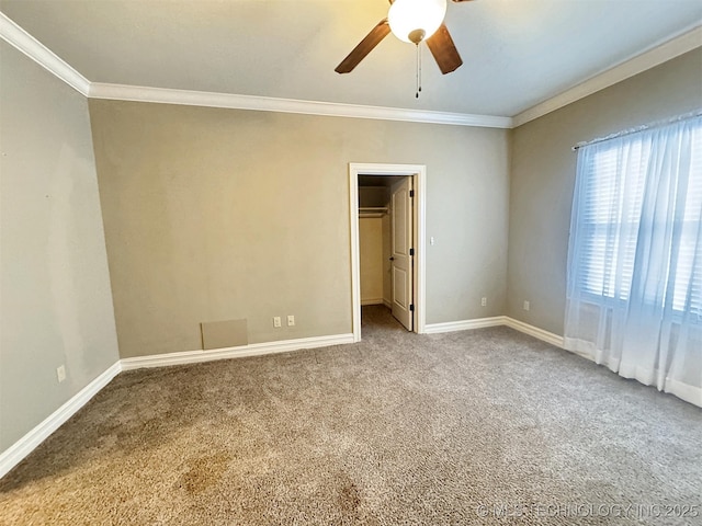 carpeted empty room with ceiling fan, ornamental molding, and baseboards