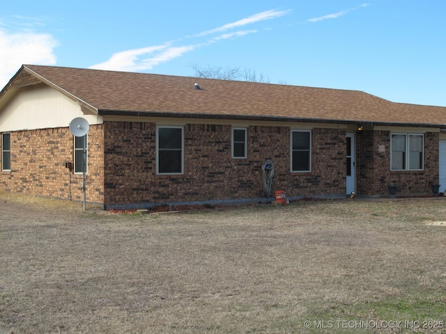 back of house featuring a shingled roof and brick siding