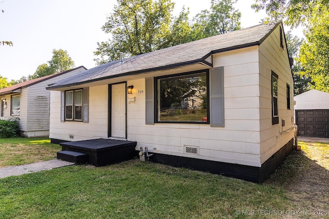 view of front facade featuring a front lawn, crawl space, and an outdoor structure