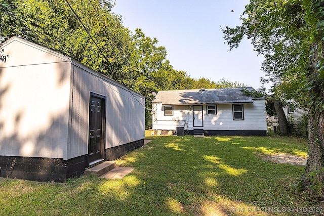 back of property featuring entry steps, crawl space, central AC unit, and a yard