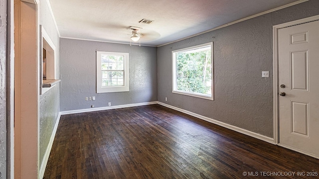 empty room with a textured wall, a wealth of natural light, and visible vents