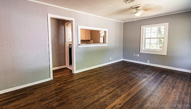 spare room featuring a textured wall, dark wood finished floors, visible vents, and baseboards