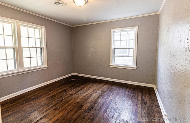 empty room with visible vents, a textured wall, ornamental molding, dark wood-type flooring, and baseboards