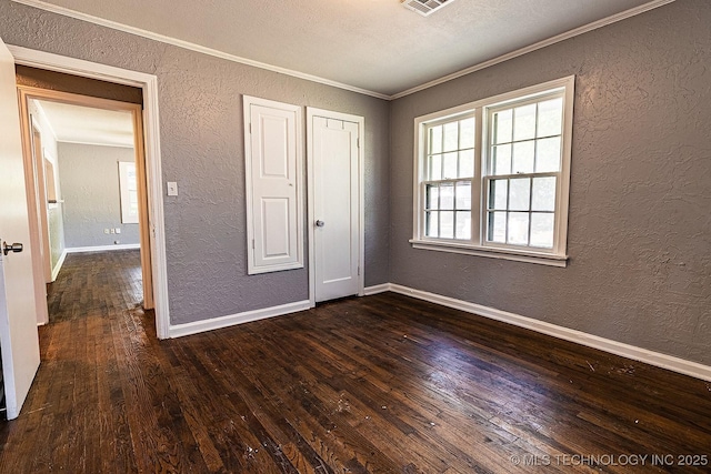 unfurnished bedroom featuring baseboards, a textured wall, dark wood finished floors, and crown molding