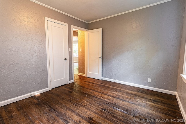 unfurnished room with crown molding, dark wood-style flooring, a textured wall, and baseboards