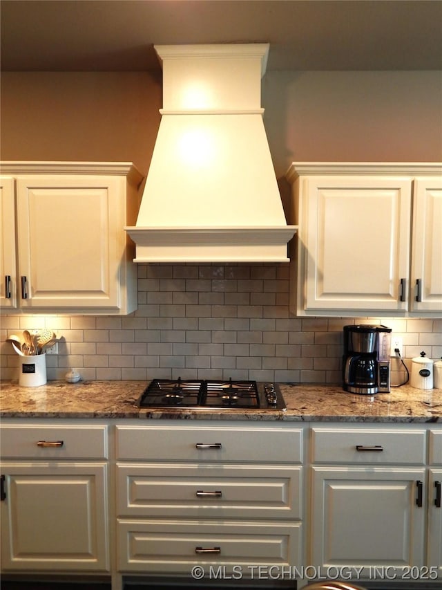 kitchen featuring backsplash, white cabinets, gas cooktop, and premium range hood