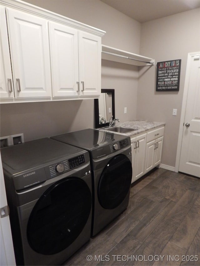 clothes washing area with baseboards, cabinet space, dark wood-style flooring, a sink, and washer and dryer