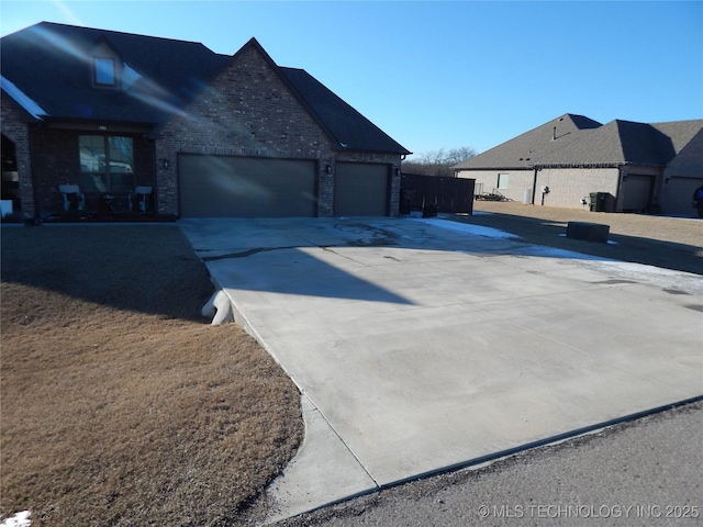 view of side of home featuring brick siding, an attached garage, and driveway