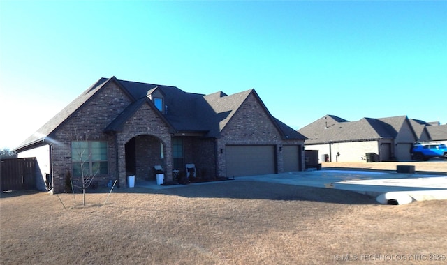 view of front facade with a front yard, an attached garage, brick siding, and driveway