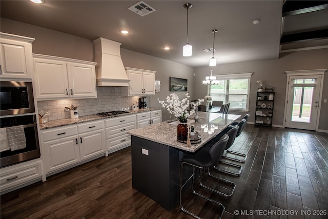 190 N Castle St, Skiatook, OK 74070 - kitchen featuring stainless steel appliances, premium range hood, white cabinetry, dark wood-type flooring, and light stone countertops