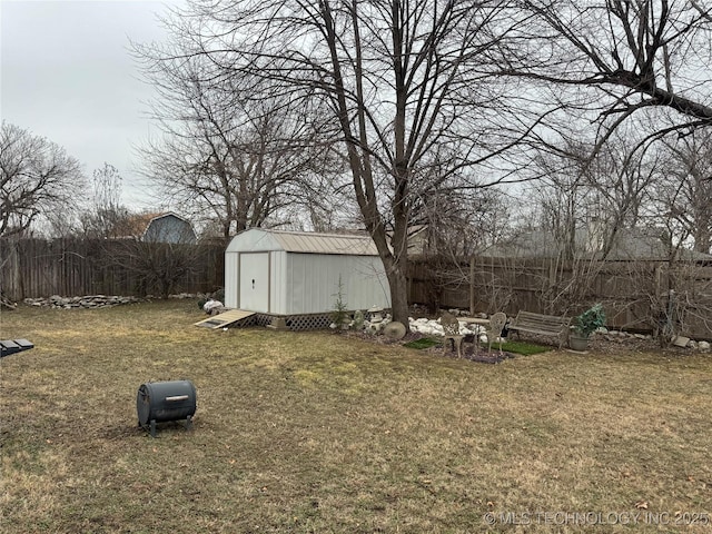 view of yard with a fenced backyard, an outdoor structure, and a storage unit