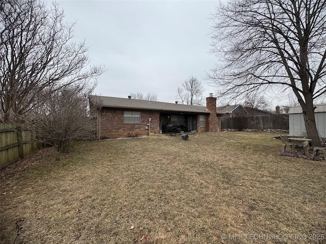 rear view of house featuring a fenced backyard, a lawn, and brick siding