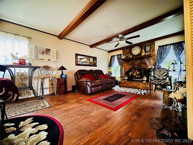 living area with a brick fireplace, wood finished floors, beam ceiling, and a healthy amount of sunlight