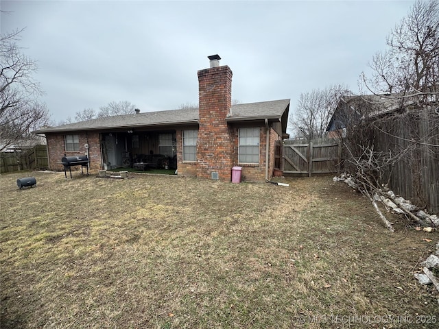 rear view of house featuring a yard, brick siding, and a fenced backyard