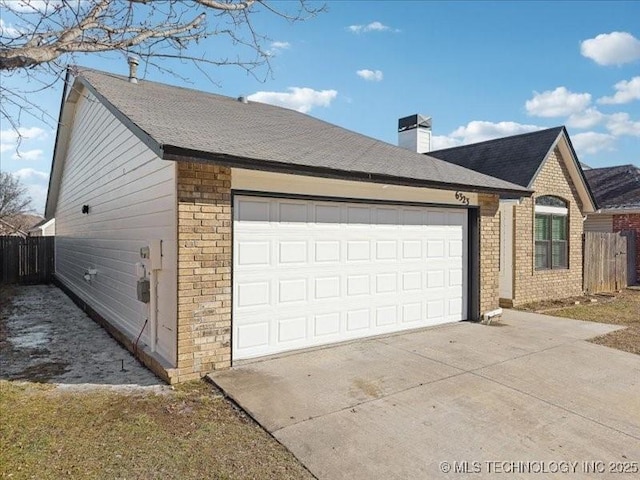 view of side of property with an attached garage, a chimney, concrete driveway, and brick siding