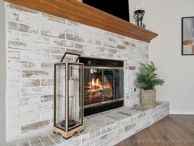 details featuring a brick fireplace, baseboards, and wood finished floors