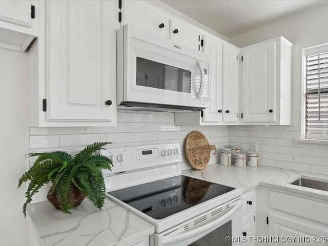 kitchen with white appliances, backsplash, light stone countertops, and white cabinets