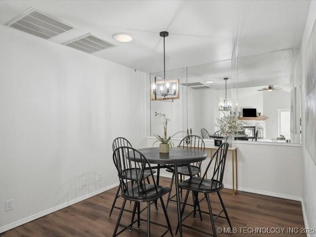 dining area with dark wood-style floors, a fireplace, baseboards, and a ceiling fan