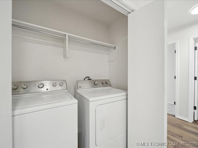 clothes washing area featuring light wood-style flooring, laundry area, and washer and clothes dryer