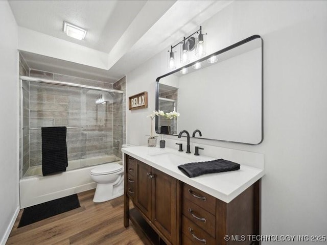 bathroom with toilet, combined bath / shower with glass door, wood finished floors, and vanity