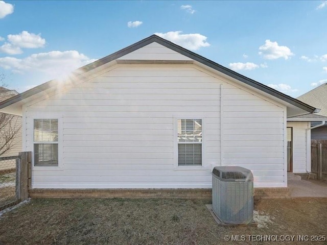 view of side of home featuring central AC unit and fence