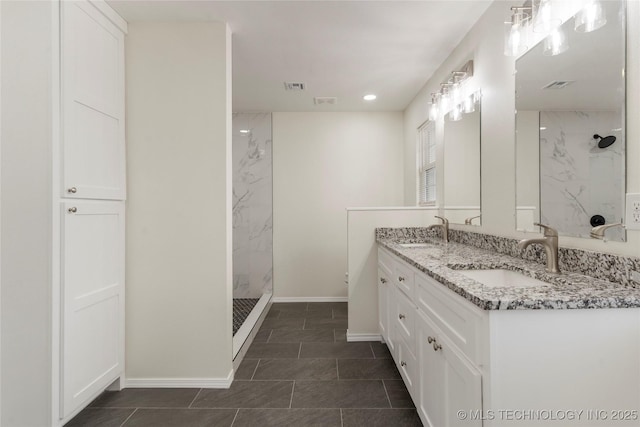 bathroom featuring double vanity, a marble finish shower, a sink, and visible vents