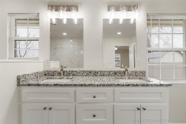 bathroom with double vanity, walk in shower, a sink, and a ceiling fan