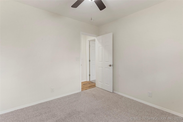 spare room with baseboards, a ceiling fan, and light colored carpet