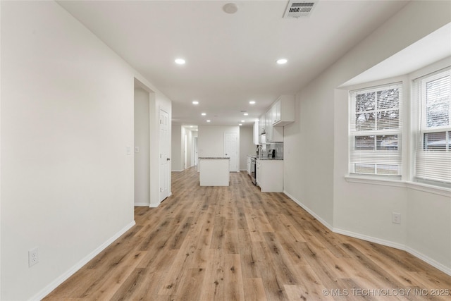 unfurnished living room with light wood-style floors, baseboards, visible vents, and recessed lighting