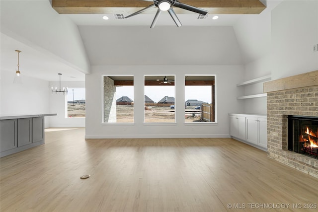 2038 E 129th St, Jenks, OK 74037 - unfurnished living room with a ceiling fan, high vaulted ceiling, a fireplace, a chandelier, and light wood-style flooring