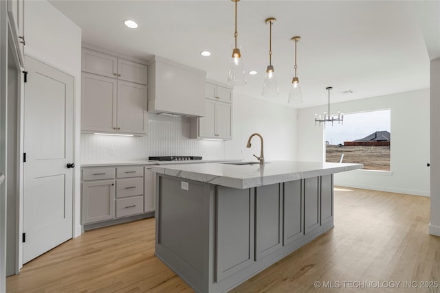 2038 E 129th St, Jenks, OK 74037 - kitchen featuring gray cabinets, premium range hood, light wood-style flooring, light stone counters, and tasteful backsplash