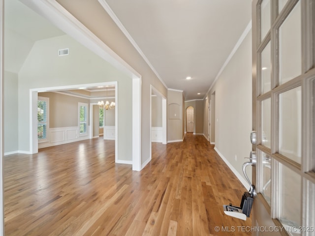 entryway with visible vents, an inviting chandelier, light wood-style floors, wainscoting, and a decorative wall