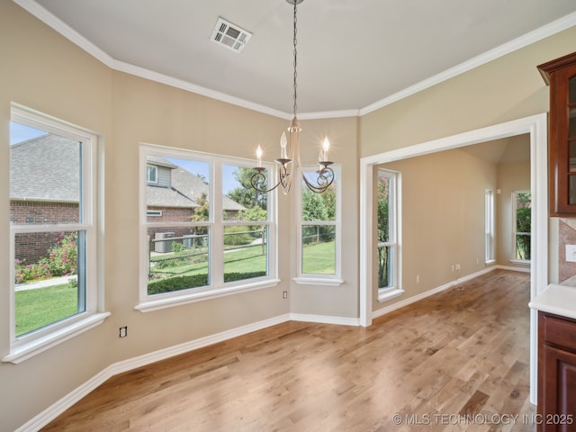 unfurnished dining area with baseboards, visible vents, an inviting chandelier, ornamental molding, and light wood-style floors