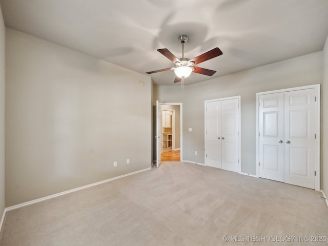 unfurnished bedroom featuring a ceiling fan, carpet flooring, baseboards, and multiple closets