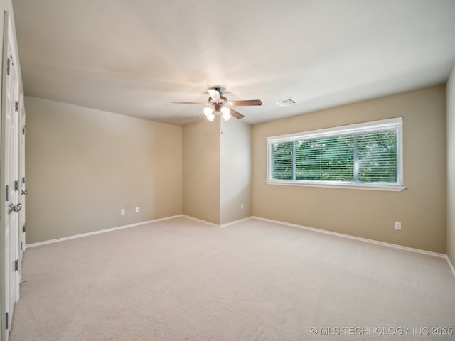 empty room featuring visible vents, light carpet, baseboards, and ceiling fan