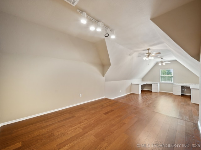 additional living space with lofted ceiling, wood finished floors, baseboards, and visible vents