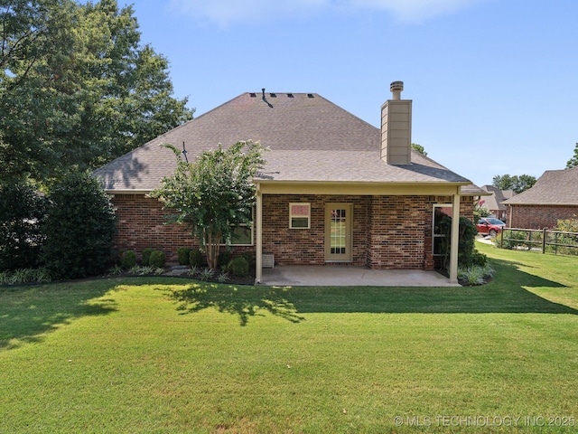 back of property with a yard, a patio, brick siding, and a chimney