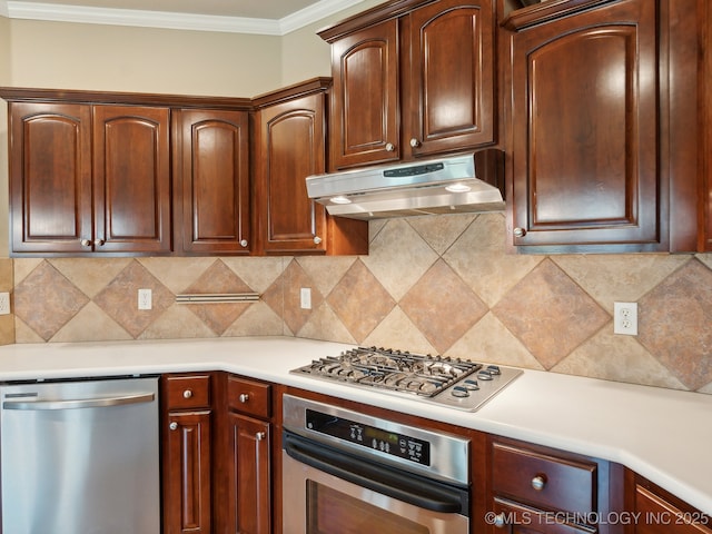 kitchen with crown molding, under cabinet range hood, light countertops, decorative backsplash, and appliances with stainless steel finishes