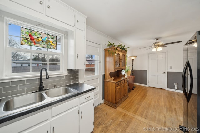 kitchen featuring freestanding refrigerator, white cabinetry, a sink, and dark countertops