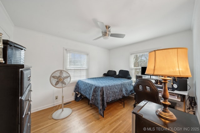 bedroom featuring light wood finished floors, visible vents, baseboards, and a ceiling fan