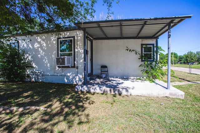 exterior space featuring a carport, a lawn, cooling unit, and stucco siding