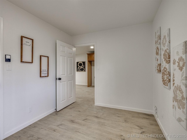 spare room featuring light wood-type flooring and baseboards