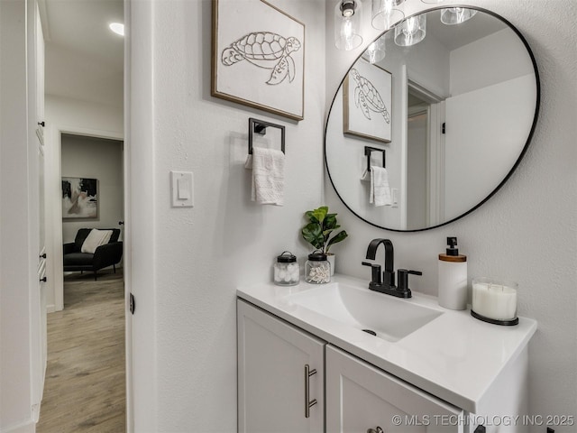 bathroom with a textured wall, wood finished floors, and vanity